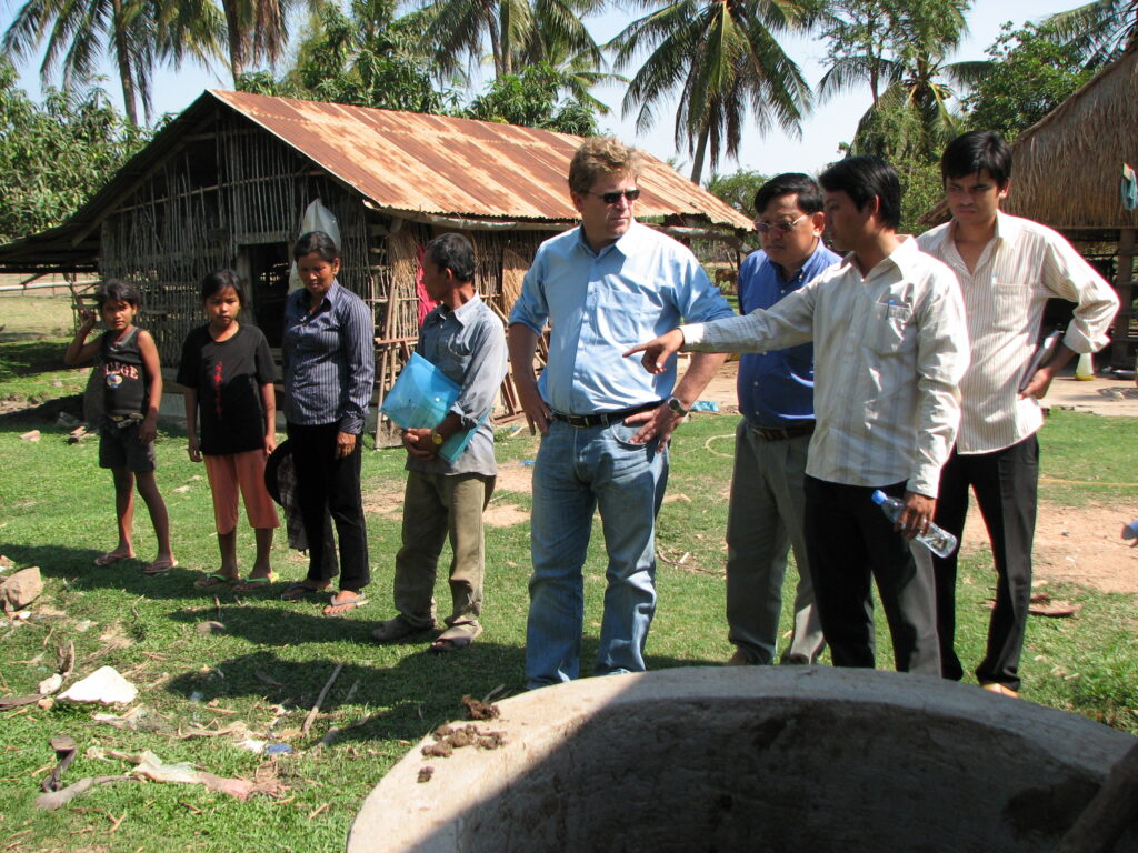Hans Guttman with community members discussing integrated rice-fish agriculture in a Cambodian village